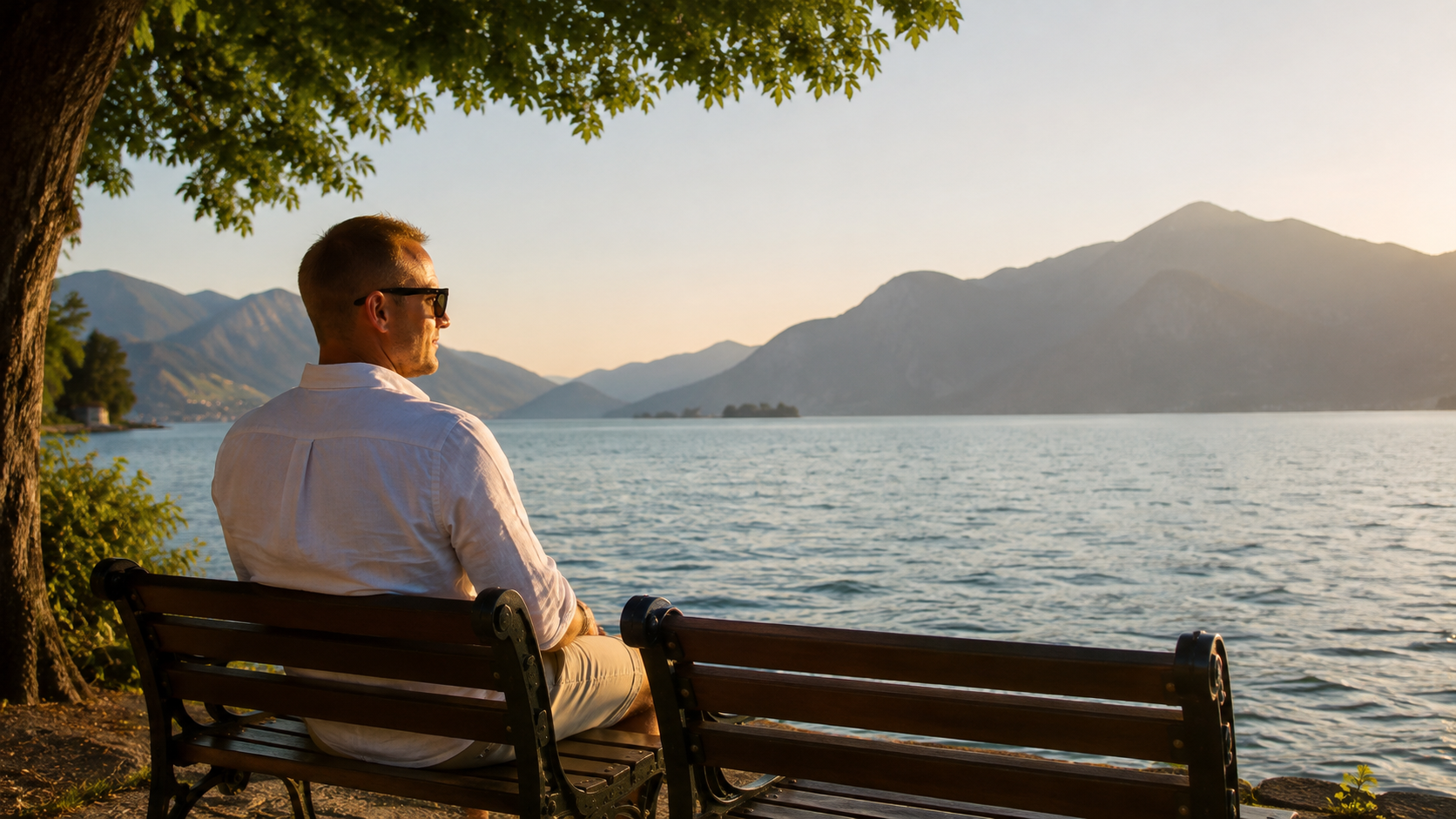 Uomo seduto davanti a un lago al tramonto riflette sul valore della presenza e dei ricordi