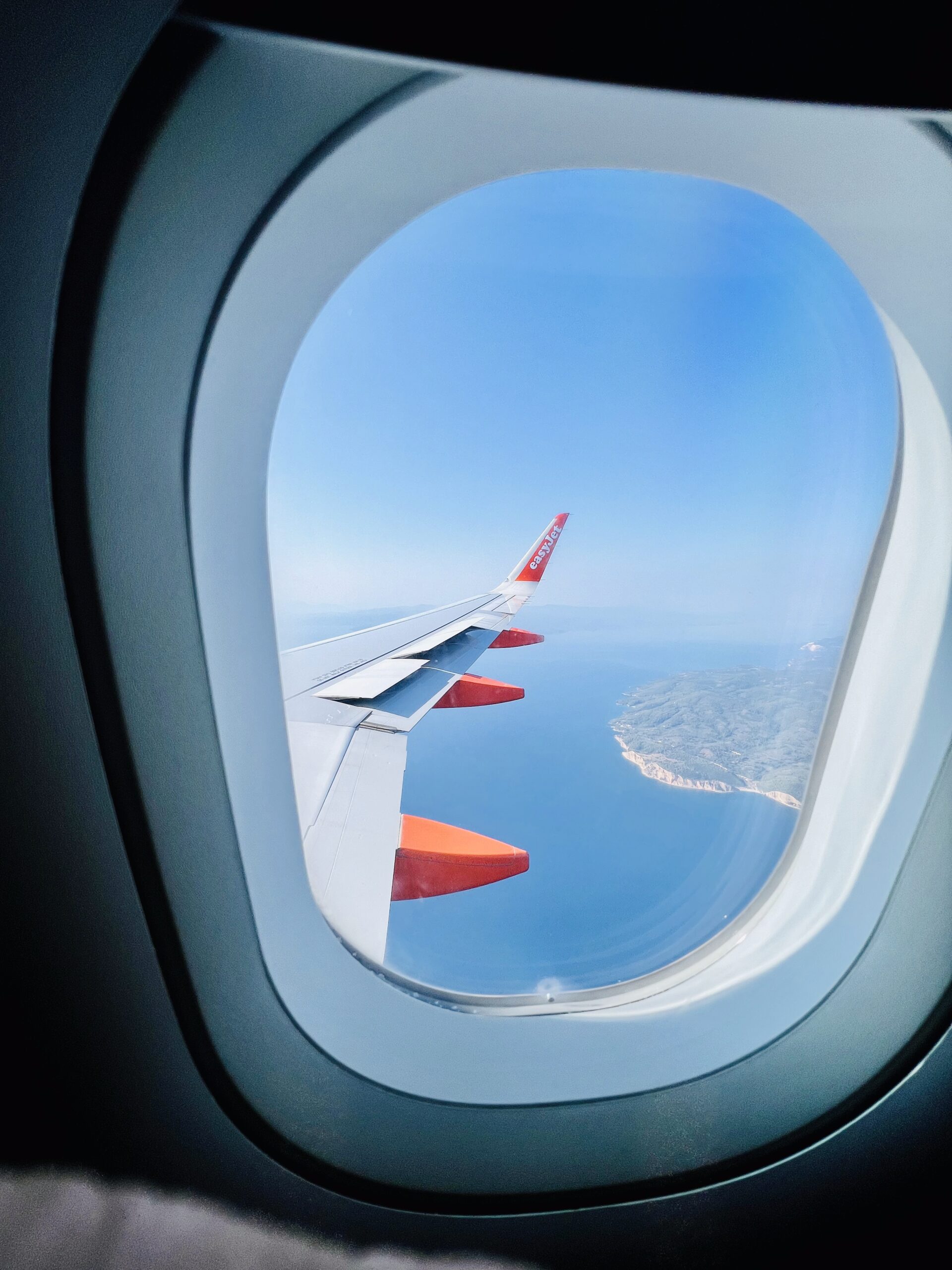 Vista dal finestrino di un aereo in volo sul mare, simbolo del passaggio da un luogo all’altro